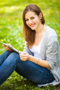 Young woman using her tablet computer while relaxing outdoors in
