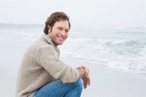 Side view portrait of a smiling casual young man relaxing at the beach