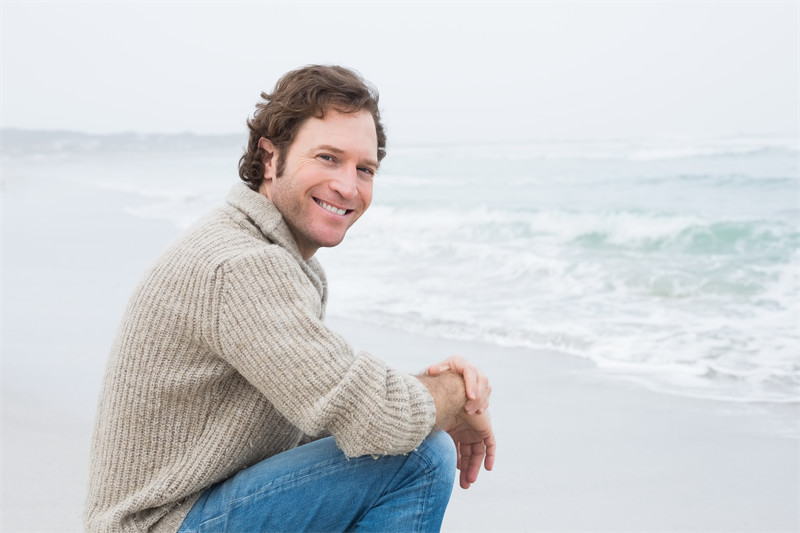 Side view portrait of a smiling casual young man relaxing at the beach