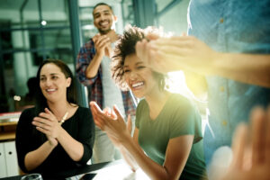 young adults smiling and clapping together in a group